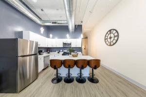 a kitchen with a counter with a refrigerator and stools at Group-Friendly 6BR Luxury Suite in Prime South Loop Location with Optional Parking and Gym Access Near McCormick Place, Soldier Field and Grant Park in Chicago