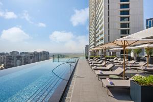 ドバイにあるPalace Dubai Creek Harbourのラウンジチェアとパラソル付きのスイミングプールを併設しています。