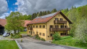 ein großes gelbes Haus mit Metalldach in der Unterkunft Ferienwohnung „Rose“ in Wiesenfelden