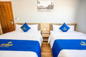 two beds in a room with blue and white sheets at Gia Nguyễn Hotel Dalat in Da Lat