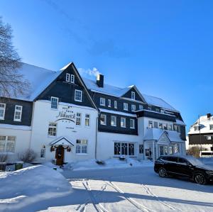 a hotel in the snow with a car parked in front at Hotel Nuhnetal in Winterberg