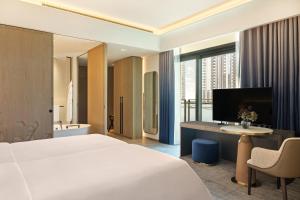a hotel room with a bed and a desk with a television at Palace Dubai Creek Harbour in Dubai