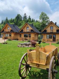 un carruaje de madera frente a una cabaña de madera en Domki Zielone Skałki, en Falsztyn