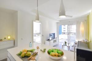 a kitchen with a bowl of fruit and vegetables on a counter at Modern Iguazu Apartment in Playa del Ingles