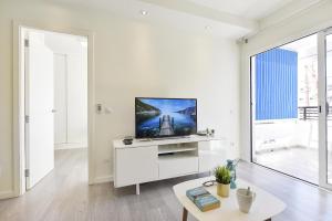 a white living room with a flat screen tv on a white cabinet at Modern Iguazu Apartment in Playa del Ingles