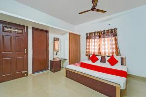 um quarto com uma cama com almofadas vermelhas e uma janela em OYO Shree Balaji Residency em Chennai