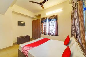 um quarto com uma cama com almofadas vermelhas e uma janela em OYO Shree Balaji Residency em Chennai