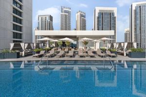 a hotel swimming pool with chairs and umbrellas at Palace Dubai Creek Harbour in Dubai