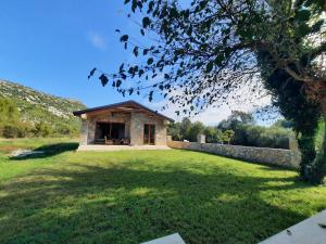 a small stone building in a field with a yard at Orahovo stone vilas in Virpazar