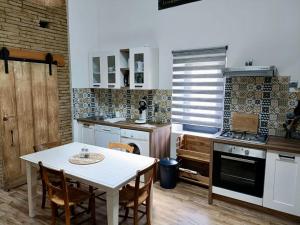 eine Küche mit einem weißen Tisch, einem Tisch und Stühlen in der Unterkunft L'Oustal in Montech