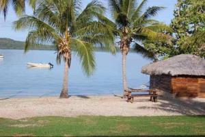 a hut and a bench on a beach with palm trees at 6 Krystal Waters Drive Havannah in Port Vila