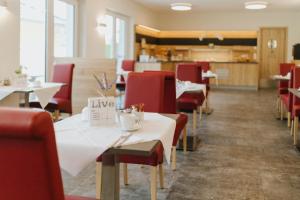 a restaurant with white tables and red chairs at Pension Casamia in Spremberg