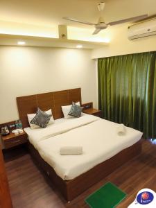 a bedroom with a large bed with a green curtain at PLUTO HOMES Dehradun in Dehradun