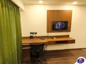 a room with a desk with a television and a chair at PLUTO HOMES Dehradun in Dehradun