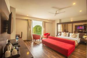 a hotel room with a bed and a red couch at Vesta Grand Central Udaipur in Udaipur +71 photos