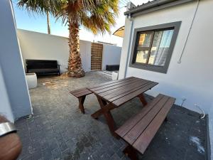 a wooden picnic table sitting next to a palm tree at 57onWYNNE in Cape Town