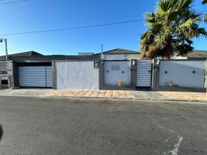 a house with two garage doors and a palm tree at 57onWYNNE in Cape Town