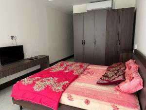 1 dormitorio con cama rosa con almohadas y TV en Cozy Private Studio with Luxurious Pool & Gym by SYM B622, en Phnom Penh