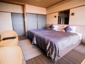 ein Schlafzimmer mit einem großen Bett und einem Stuhl in der Unterkunft LiVEMAX RESORT Kyotango Sea Front in Kyōtango