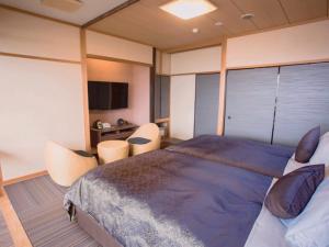 a bedroom with a large bed and two chairs at LiVEMAX RESORT Kyotango Sea Front in Kyotango