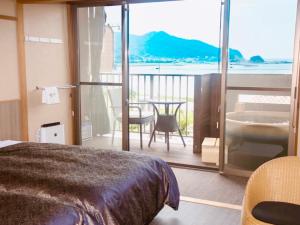 1 Schlafzimmer mit einem Bett und einem Balkon mit einem Tisch in der Unterkunft LiVEMAX RESORT Kyotango Sea Front in Kyōtango