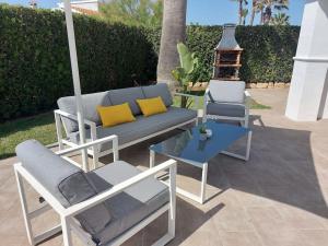 2 sedie, un divano e un tavolo su un patio di Villa Juanes. Encanto, privacidad y relax. a Cala'n Bosch