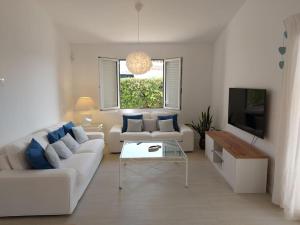 un soggiorno con divano bianco e TV di Villa Juanes. Encanto, privacidad y relax. a Cala'n Bosch