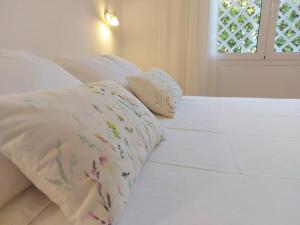 un letto bianco con due cuscini e una finestra di Villa Juanes. Encanto, privacidad y relax. a Cala'n Bosch