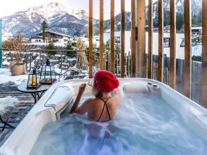 a woman sitting in a hot tub on a deck at Alpegg Chalets in Waidring