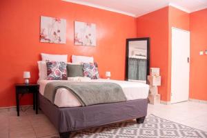 a bedroom with orange walls and a large bed at Laha Apartment 3 in Maun