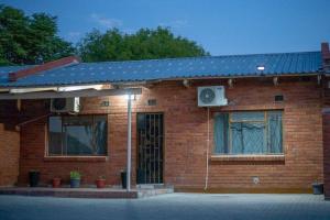 a red brick house with a blue roof at Laha Apartment 3 in Maun