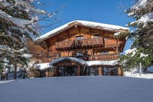 a log cabin in the snow with snow covered trees at Chalet Luxe Les Orchis Alpe d'Huez in LʼHuez