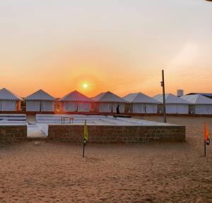 a sunset over a beach with tents in the sand at Desert Stay Camp in Sām