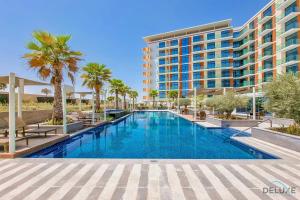 a swimming pool with palm trees and a building at Cozy Studio in Damac Celestia A Dubai South by Deluxe Holiday Homes in Dubai