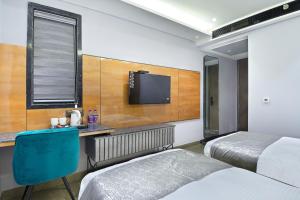 a hotel room with two beds and a desk and a tv at Hotel Uptown Delhi in New Delhi