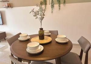 een houten tafel met stoelen en een vaas met bloemen bij Tranquil Suite, MKH Boulevard 2 in Kajang