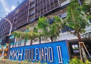 a building with a sign in front of a palm tree at Tranquil Suite, MKH Boulevard 2 in Kajang