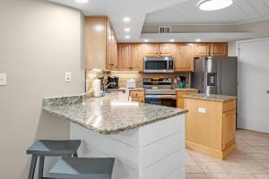 - une cuisine avec des placards en bois et un plan de travail en granit dans l'établissement Summer House 405A, à Romar Beach