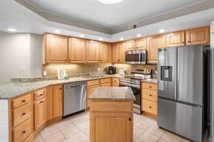 une cuisine avec des armoires en bois et des appareils en acier inoxydable dans l'établissement Summer House 405A, à Romar Beach