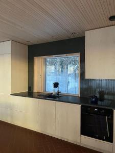 cocina con encimera negra y ventana en A unique lakeside cottage, en Rovaniemi