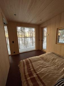 a bedroom with two windows and a bed in it at A unique lakeside cottage in Rovaniemi