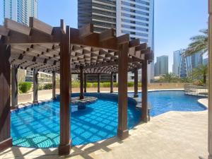 a large swimming pool with a wooden pergola at Brand New 1BDR Dubai Marina -Close to Metro in Dubai