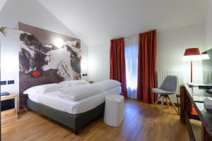 una camera d'albergo con letto e scrivania di Hotel Berthod a Courmayeur