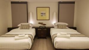 una camera con due letti con lenzuola bianche di Villa Lantara Chiangmai a Chiang Mai