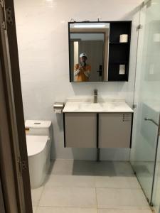 a person taking a picture of a bathroom with a mirror at Novaworld Phan Thiết- 7Days mart in Phan Thiet