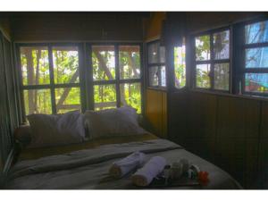 Schlafzimmer mit einem Bett mit Handtüchern und Fenstern in der Unterkunft Karang Aji Beach Villa in Cisolok