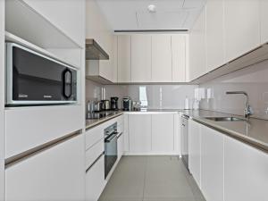 a white kitchen with white cabinets and a microwave at Contemporary Designed 1BDR - Address Beach JBR in Dubai