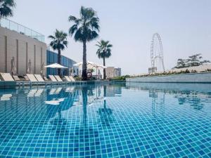 a large swimming pool with chairs and palm trees at Contemporary Designed 1BDR - Address Beach JBR in Dubai