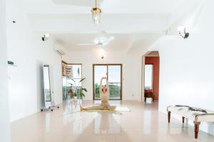 a woman doing yoga in the middle of a room at Tropical Soul Okinawa - 135平米1453sqft - Max10 in Teruya