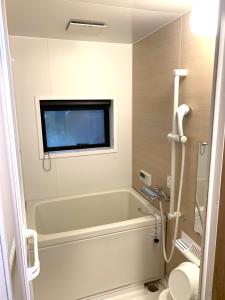 a bathroom with a tub and a tv on the wall at THE FARM Resort Japan in Katori